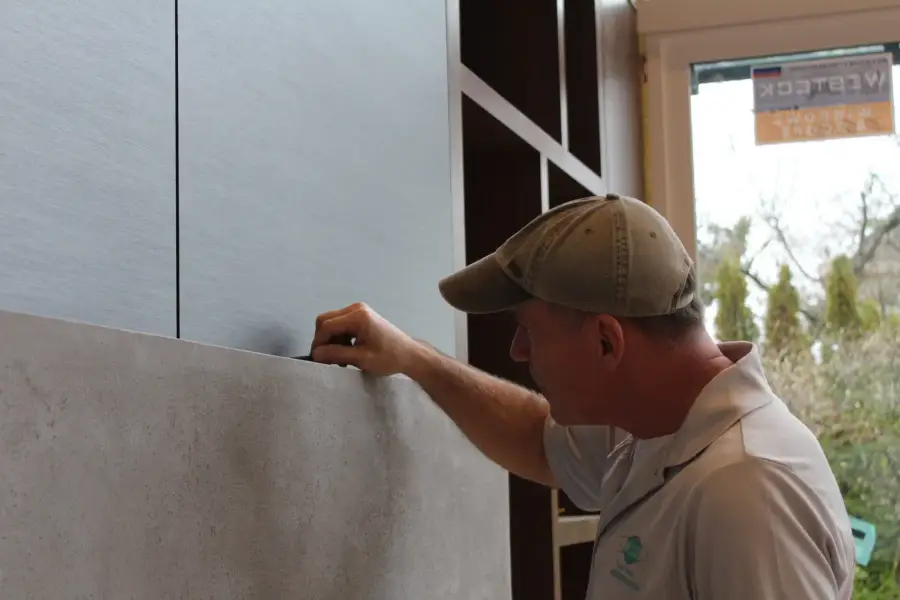 Installer smoothing a stone-look Bodaq film onto a wall panel